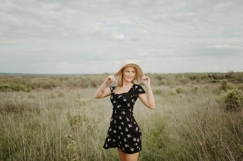黑色和白色的圆点裙，站在绿草地上的女人 · 免费素材图片