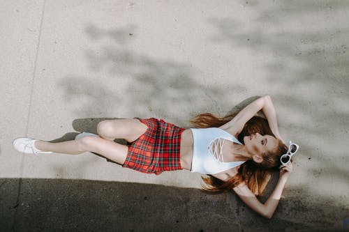 白色背心和躺在白色的沙滩上的红色格子裙的女人 · 免费素材图片