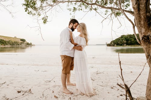 暑假期间在沙滩上拥抱的优雅情侣 · 免费素材图片