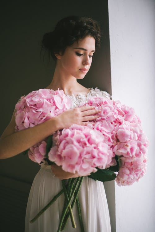 拿着桃红色花花束的桃红色和白色花服的妇女 · 免费素材图片