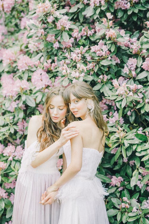 站在粉红色的花朵旁边的白色连衣裙的女人 · 免费素材图片