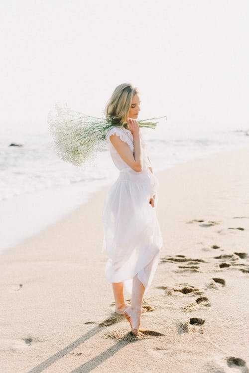 在沙滩上散步的白裙子的女人 · 免费素材图片