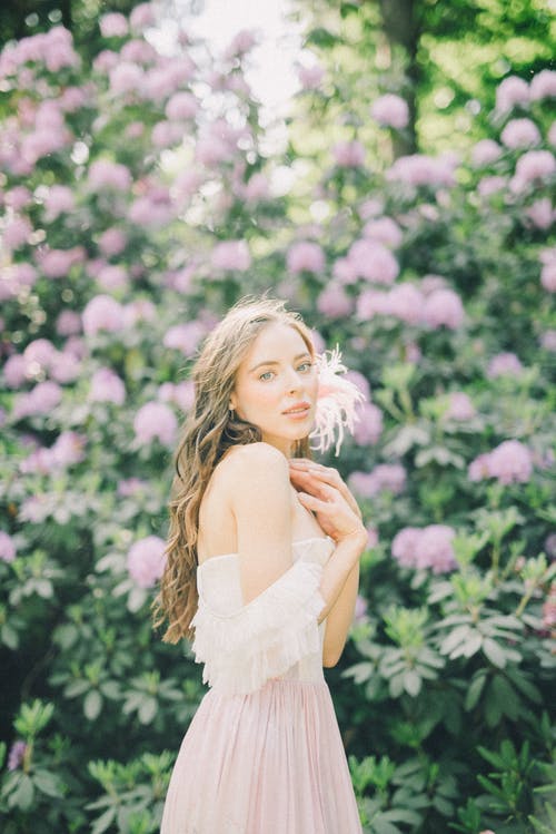 站在粉红色的花朵附近的白色连衣裙的女人 · 免费素材图片