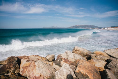 在蓝天的衬托岩石海岸上运行的海浪 · 免费素材图片