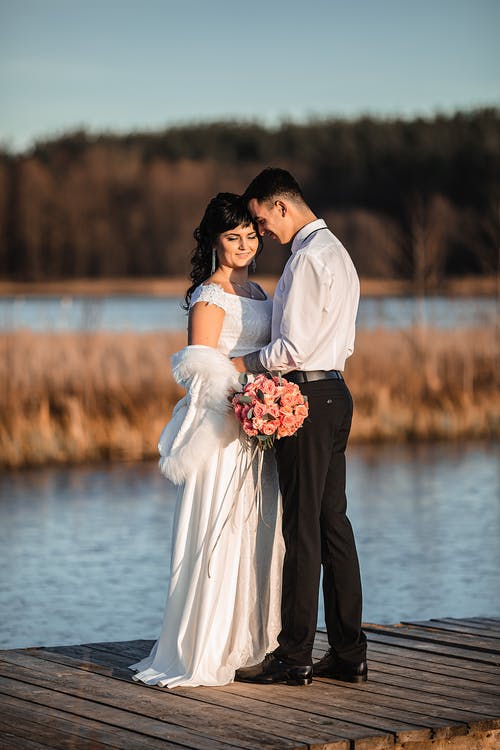 幸福的新婚夫妇拥抱在木码头上的爱情 · 免费素材图片