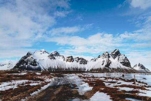 靠近海洋的岩石和天空下的雪域 · 免费素材图片