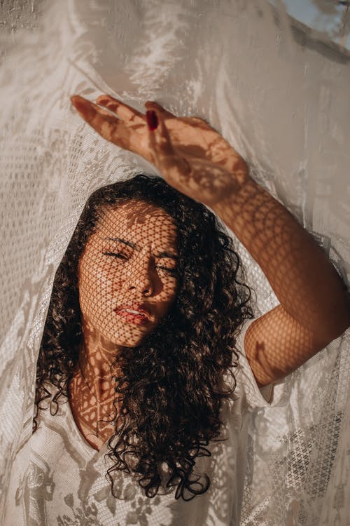 时尚无聊的女人，用窗帘在脸上的阴影 · 免费素材图片