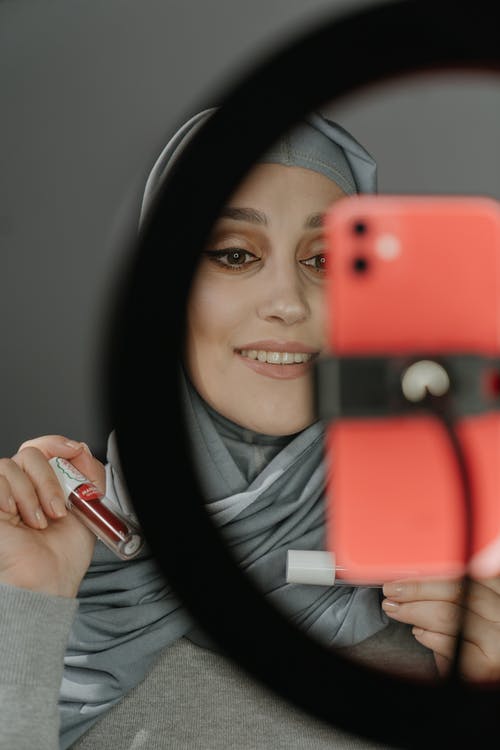 拿着红色智能手机的灰色毛衣的女人 · 免费素材图片
