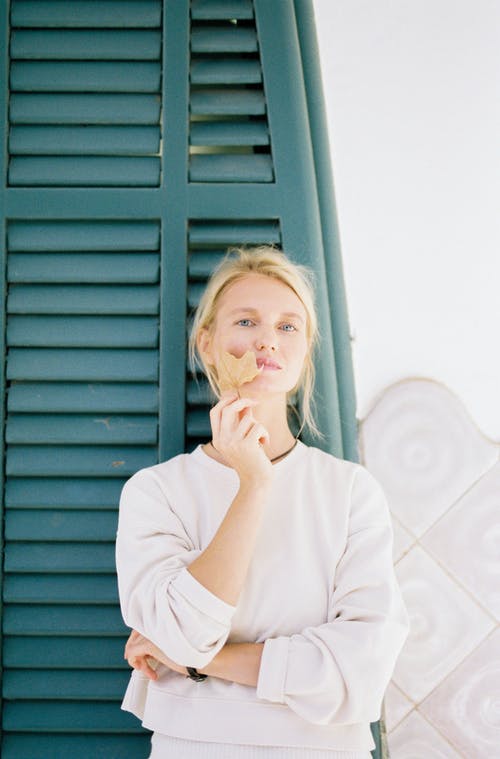 坐在蓝色木门旁边的白色长袖衬衫的女人 · 免费素材图片