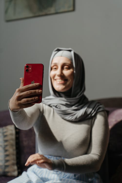 拿着红色智能手机的灰色头巾的女人 · 免费素材图片