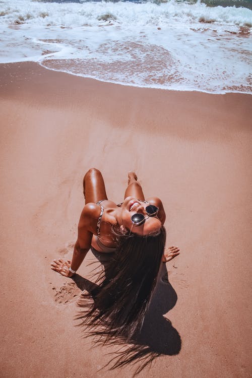 合适的女人在沙滩上晒日光浴 · 免费素材图片