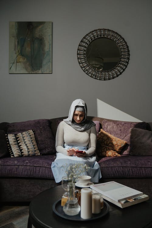 白色头巾的女人坐在棕色沙发上 · 免费素材图片