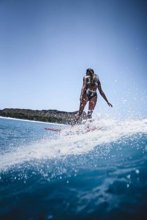 积极适合女人在晴朗的一天在海洋中冲浪 · 免费素材图片