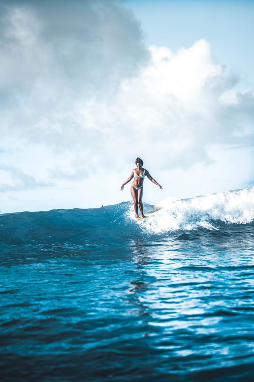 合适的女人站在海浪冲浪板上 · 免费素材图片