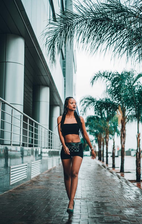 黑人女士走在空荡的人行道上与热带树木 · 免费素材图片