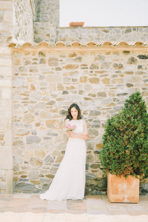 站在绿色的植物旁边的白色婚纱的女人 · 免费素材图片