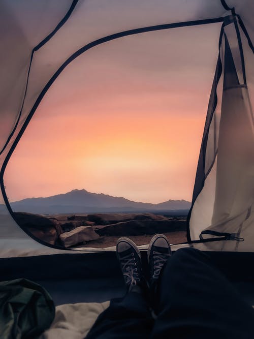 旅行者躺在帐篷里，享受着明亮的夕阳光 · 免费素材图片