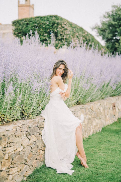 坐在紫色的花旁的白色婚纱的女人 · 免费素材图片
