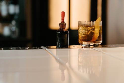 透明水杯旁边的棕色玻璃瓶 · 免费素材图片