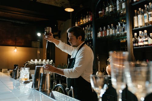 白色长袖衬衫倒在透明酒杯上的酒的男人 · 免费素材图片