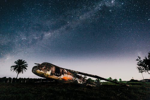 晚上在明亮的天空下的土地上坠毁的飞机 · 免费素材图片