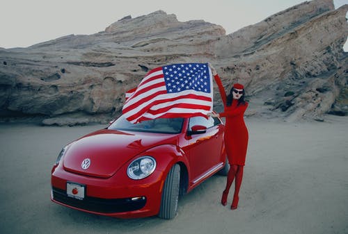 女人旁边的红色汽车的照片 · 免费素材图片