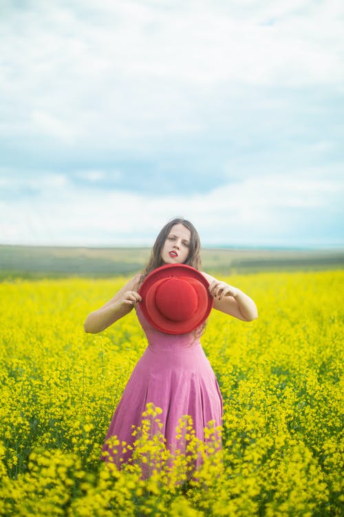站在黄色的花场上的粉红色裙子的女孩 · 免费素材图片