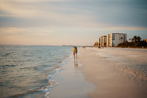 匿名夫妇在日落时站在沙滩上 · 免费素材图片