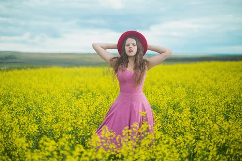 站立在黄色花田的桃红色礼服的妇女 · 免费素材图片