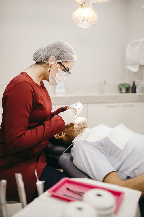 面罩无法识别的牙医检查病人的牙齿 · 免费素材图片