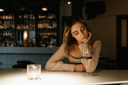 坐在桌子旁边与酒杯的棕色长袖衬衫的女人 · 免费素材图片