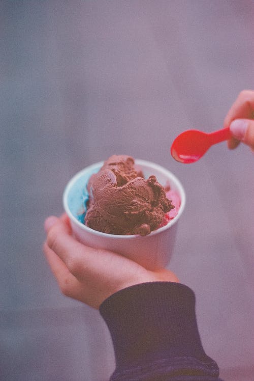 人拿着冰淇淋用红色的勺子 · 免费素材图片