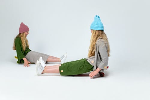 穿绿色外套和蓝色针织帽坐在白色地板上的女人 · 免费素材图片