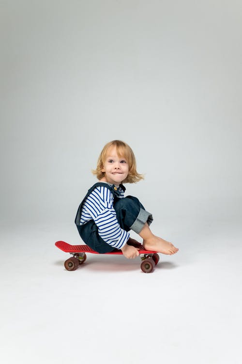 蓝色和白色的条纹的长袖衬衫，坐在红色和白色的塑料骑的女孩 · 免费素材图片