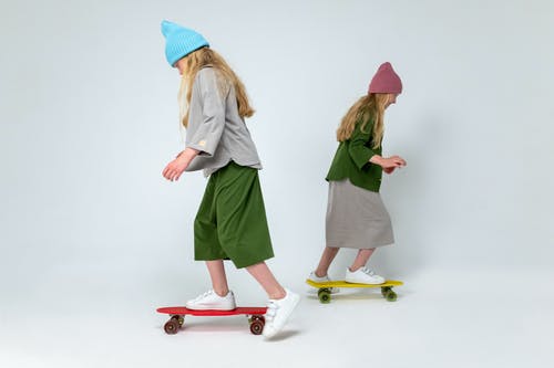 2名穿着绿色的女人站在红色和白色的滑板上 · 免费素材图片