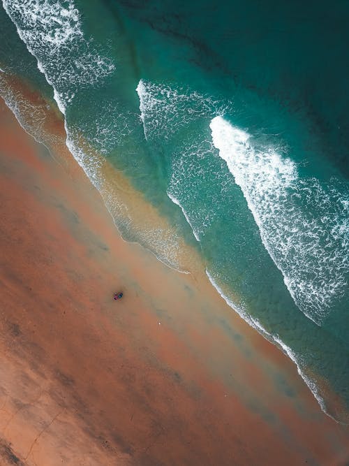 波浪状的绿松石海在阳光下洗沙岸 · 免费素材图片