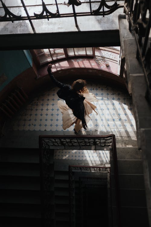 黑色外套和棕色的裤子，在棕色的混凝土楼梯上跳跃的人 · 免费素材图片