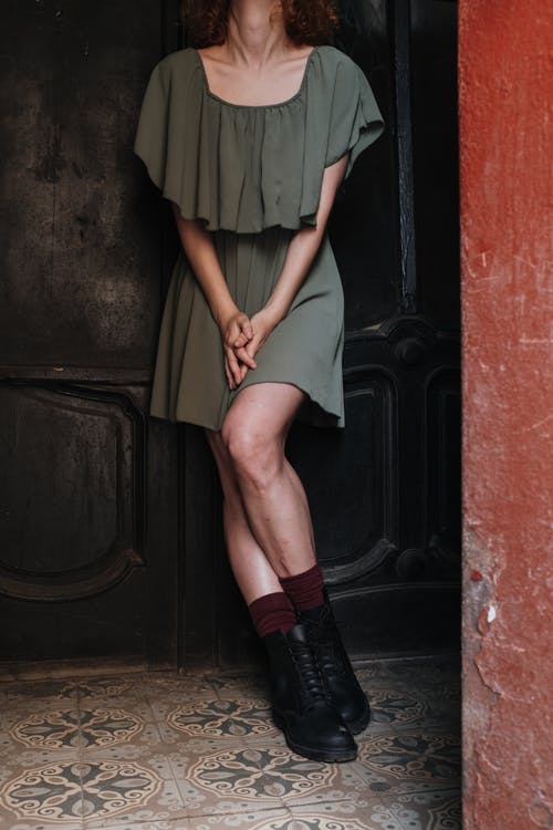 绿色的裙子和黑色的皮靴，站在棕色的木门旁边的女人 · 免费素材图片