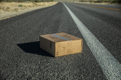 灰色的沥青路面上的棕色纸板箱 · 免费素材图片