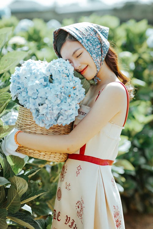 性格开朗的亚裔女子，闻花香 · 免费素材图片