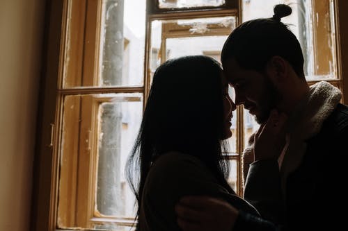 男人和女人在窗户附近接吻 · 免费素材图片