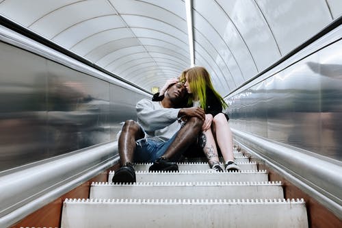 黑色背心和蓝色牛仔短裤，坐在自动扶梯上的女人 · 免费素材图片