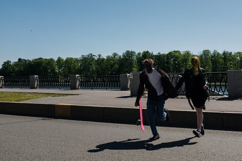黑色外套和粉红色的裤子，在灰色的混凝土道路上行走的女人 · 免费素材图片