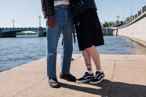 蓝色牛仔牛仔裤和黑色皮夹克站在棕色的水泥地板上的女人 · 免费素材图片