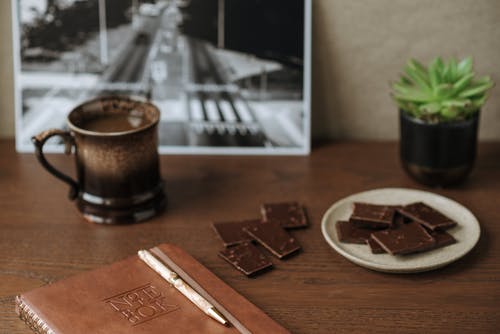 笔记本附近杯咖啡和巧克力 · 免费素材图片