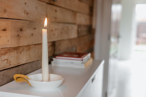 堆书和木墙附近的闪亮蜡烛 · 免费素材图片