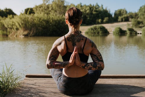 匿名的女人在反对湖码头上练瑜伽 · 免费素材图片