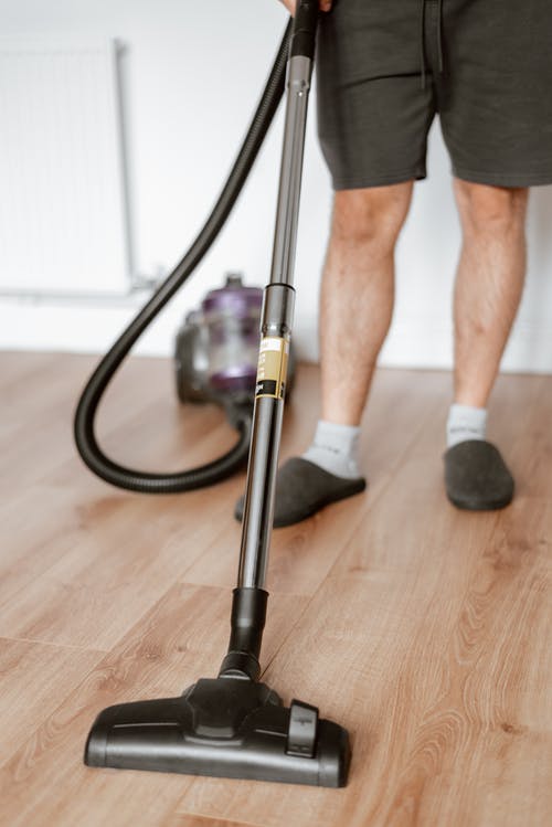男人用吸尘器在家里打扫地板 · 免费素材图片