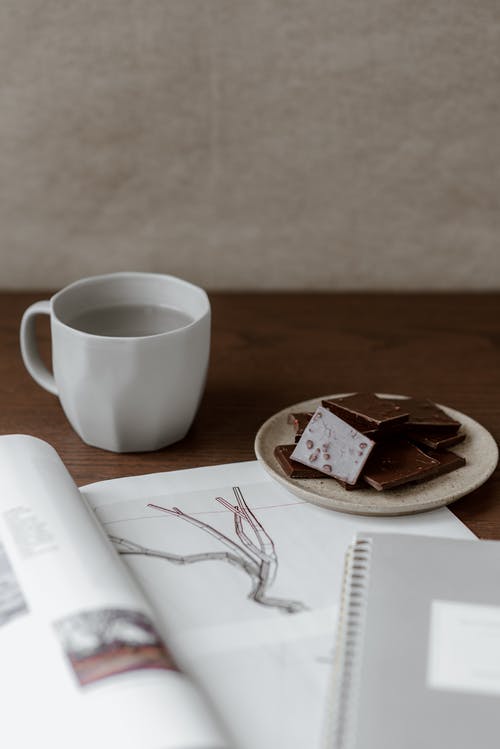 素描本和杯子附近的牛奶巧克力 · 免费素材图片