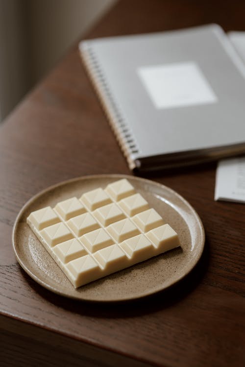 桌上的笔记本附近的美味白巧克力 · 免费素材图片